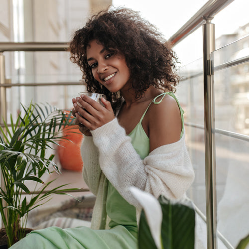 Woman holding a mug in a cozy indoor setting with plants