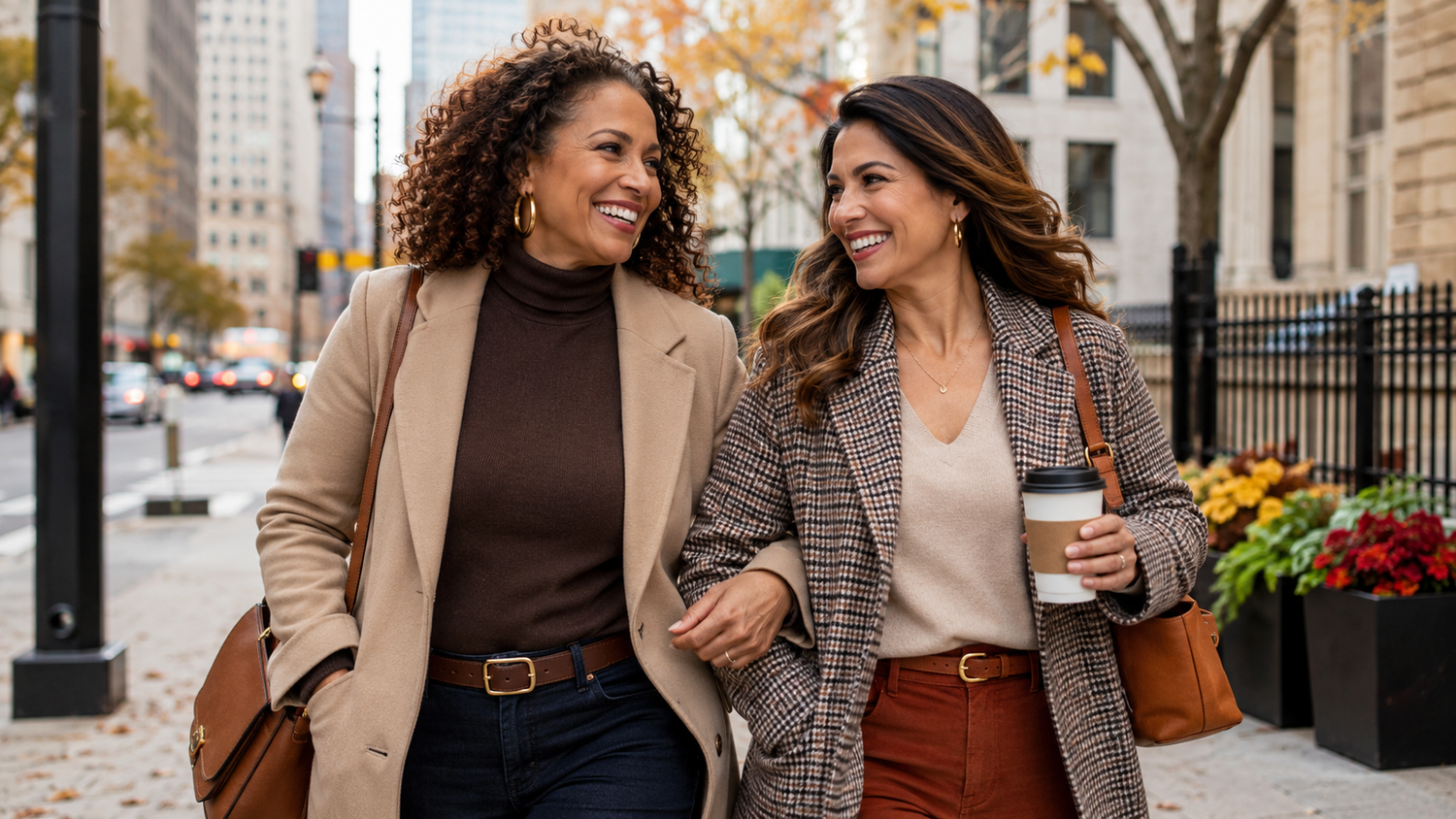 2 women smiling in fall clothes. Walking on the street.