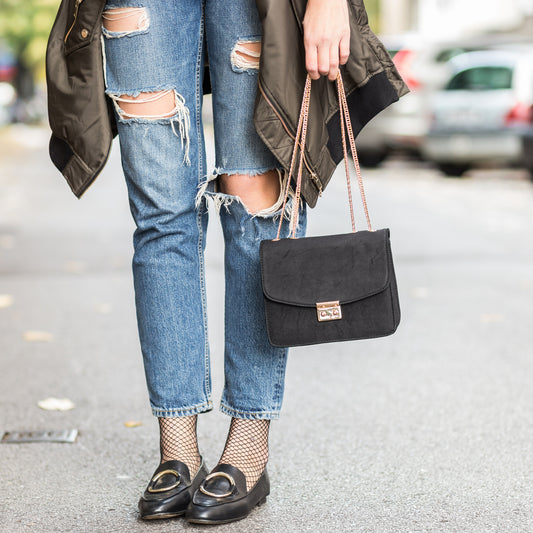 Women wearing jeans and flats. Holding a purse.