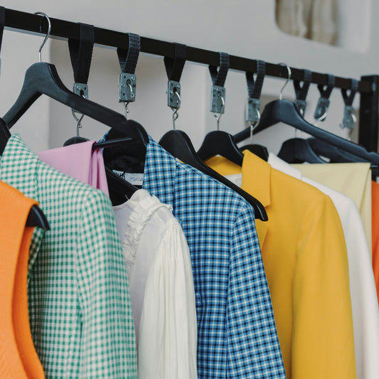 Several spring colored clothing hanging on a rack.